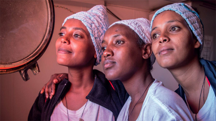 3 femmes africaines souriant en regardant par le hublot d'un navire