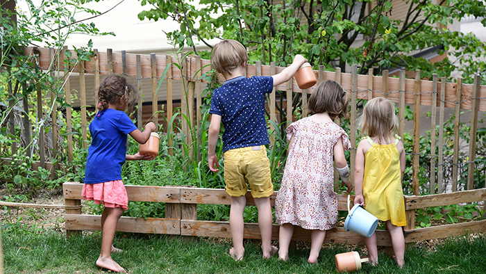 Enfants pieds nus, arrosant des plantations dans le jardin de leur crèche